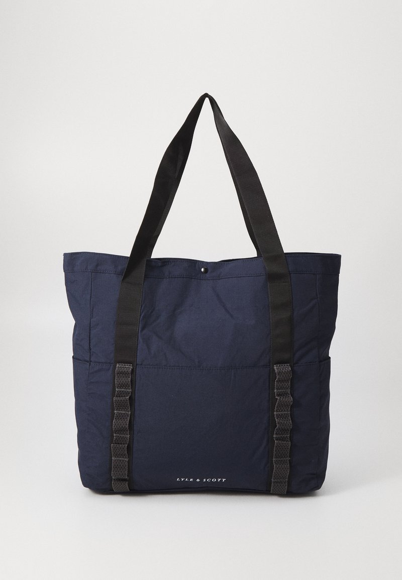 Bolsa tote de color azul marino hecha de nailon con un diseño estructurado, que cuenta con asas de web de color negro y un cierre a presión. Logotipo plateado en la parte inferior.