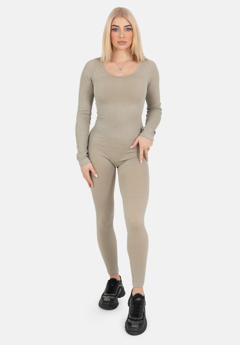Geribbelde, lange mouwen jumpsuit in lichtbeige, aansluitend ontwerp, gecombineerd met zwarte sneakers met glinsterende accenten. Eenvoudige ronde halslijn, zonder patronen.