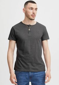 Ciemnoszary t-shirt z krótkim rękawem, z dekoltem henley i trzema guzikami. Posiada subtelny tłoczony wzór na lewej stronie klatki piersiowej.