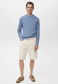 Suéter de canalé azul claro, pantalones cortos crema y zapatos color marrón claro. El conjunto presenta un corte holgado y un diseño simple, sin patrones ni acentos.