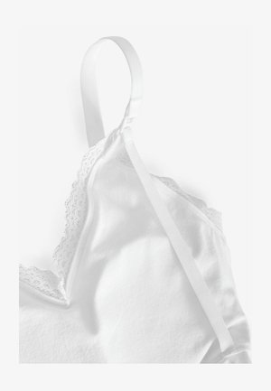 Bela kamizola z čipkastim robom ob izrezu, z nastavljivimi satenastimi naramnicami. Mehka bombažna tkanina z gladko teksturo.