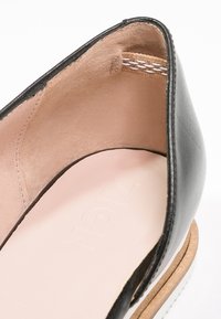 Czarna skórzana półbuty o niskim kroju, z jasnobrązowym wnętrzem ze skóry i jasnoróżową wkładką. Charakteryzują się gładką teksturą i minimalnym przeszyciem.