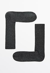 Chaussettes côtelées gris foncé disposées en forme diagonale, avec une texture douce et un bout arrondi.