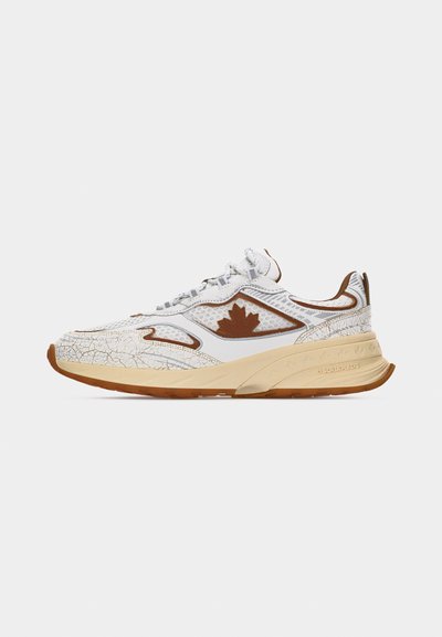 Baskets blanches et beiges avec un logo feuille d'érable marron, texture en mesh et cuir craquelé, semelle épaisse beige et bout rond sur un fond uni.