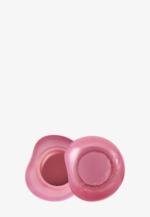 Petit contenant cosmétique rond rose avec couvercle amovible, montrant un blush ou baume crémeux à l'intérieur.