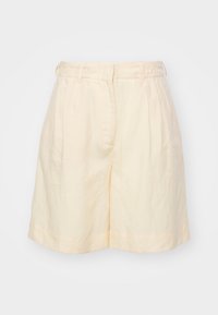 Pantaloni corti in lino beige con vestibilità ampia, frontale pieghettato e orlo cuffato. Presentano una vita con passanti per la cintura e tasche laterali.