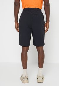 Czarne szorty wykonane z lekkiego materiału, z elastycznym pasem, bocznymi kieszeniami oraz gładką teksturą, charakteryzujące się prostą nogawką.