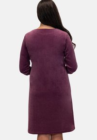 Langsleeve paars fluwelen jurk met een ronde halslijn, tot halverwege de kuit, met een zachte textuur en een eenvoudige silhouet.