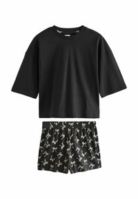 Black cotton T-shirt with short sleeves and loose fit, paired with black shorts featuring a white bow pattern. Elastic waistband on shorts.