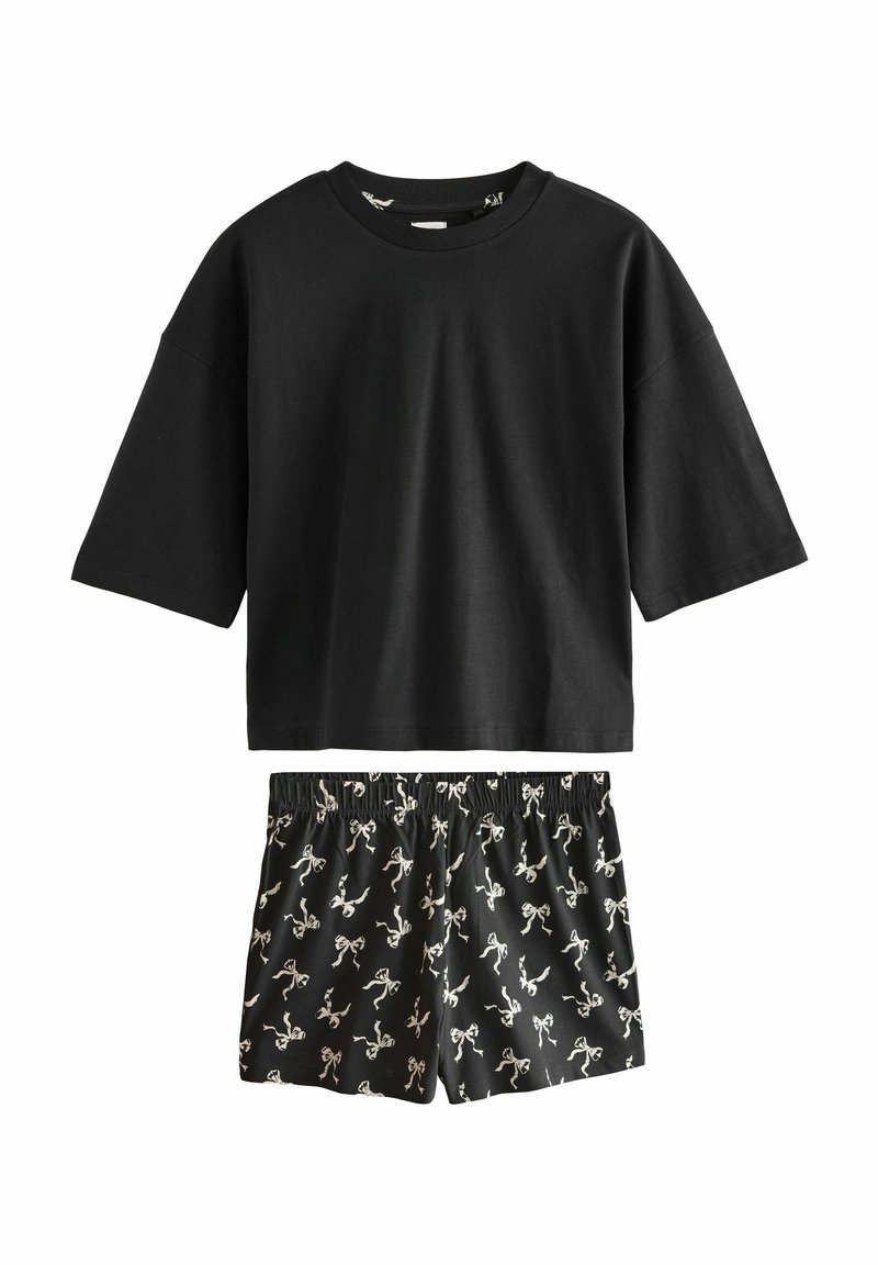 Black cotton T-shirt with short sleeves and loose fit, paired with black shorts featuring a white bow pattern. Elastic waistband on shorts.