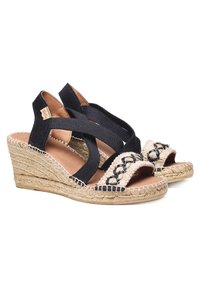 Mustad espadrillid kootud elastsete rihmadega, jute-nööriga tallad ning dekoratiivne põimitud detail varba piirkonnas.