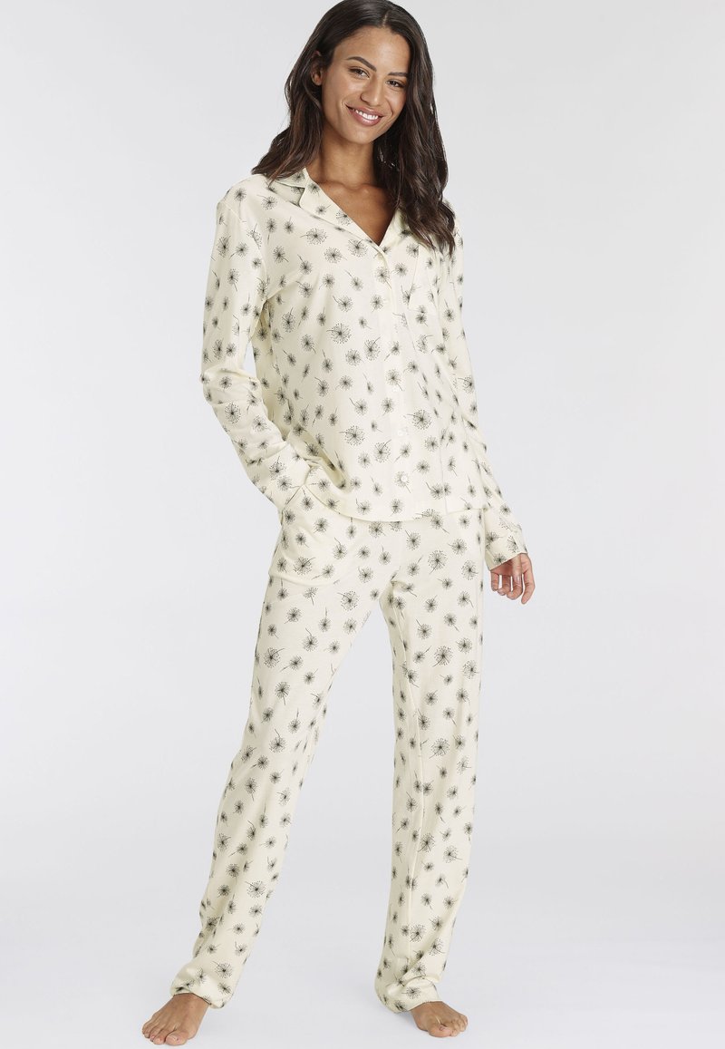 Crème-kleurig pyjama set bestaande uit een button-up overhemd met lange mouwen en bijpassende broek in een zwart bloemenpatroon, gemaakt van zachte stof.