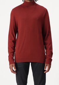 Pull-over en tricot rouge avec un col montant, des manches longues et des poignets et un ourlet côtelés. Texture lisse ; design minimaliste.