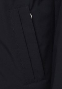 Marinejacke mit einer Reißverschlusstasche, glatter Textur und scharfen Nähdetails. Entworfen für Funktionalität und Langlebigkeit.