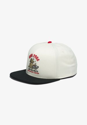 Hvid og sort kasket med flad skygge og rød knap, med broderet hunde-DJ, vinylplade, musiknoder og teksten "Vans 1966 SK8-Hi Note."