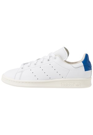 Witte lage Adidas sneaker met geperforeerde zijstrepen, witte veters, off-white zool en blauw hielstuk.