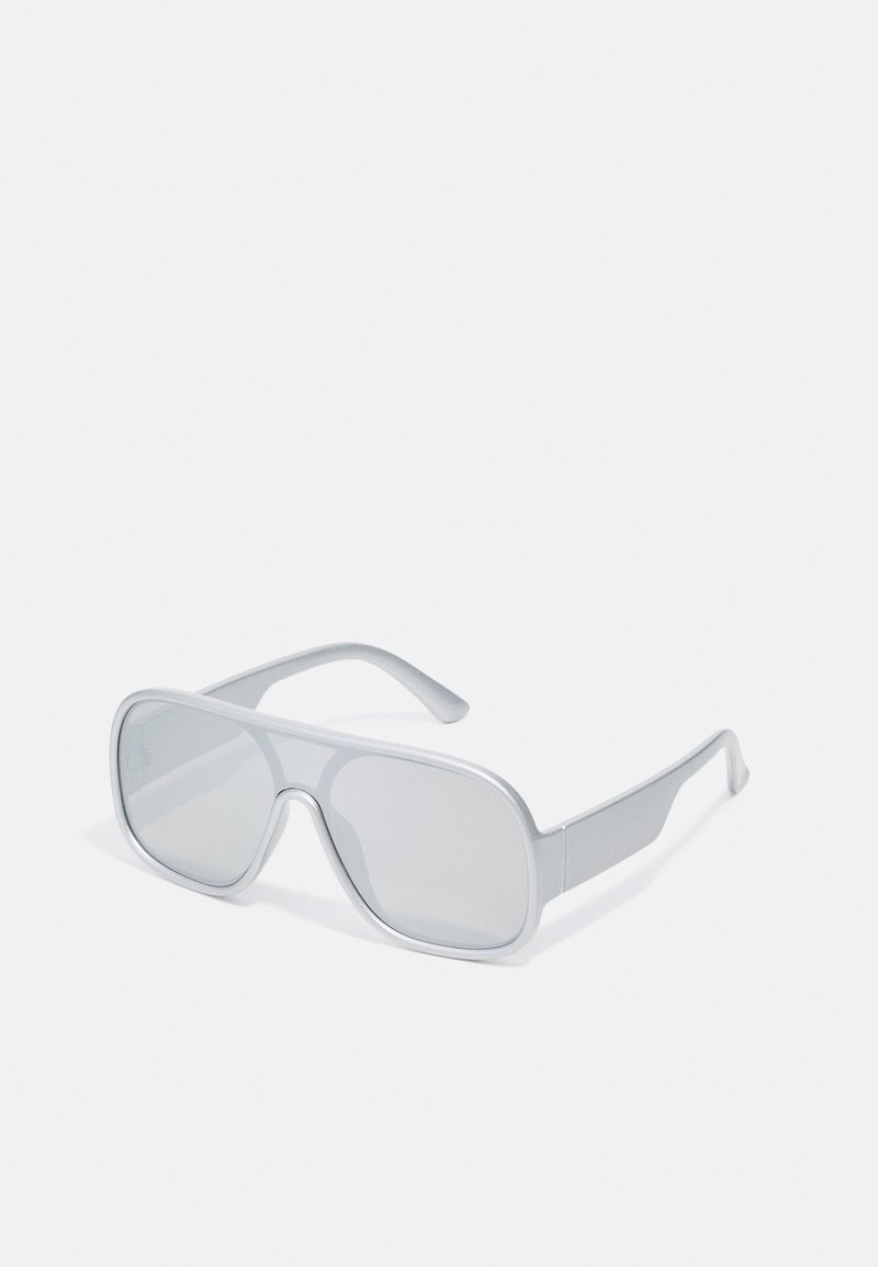 Lunettes de soleil surdimensionnées grises avec une monture en plastique élégante, des verres plats et des branches droites. Fini mat sans embellissements supplémentaires.