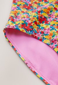 Ziedu raksta audums spilgtās krāsās (rozā, sarkanā, dzeltenā, zilā) ar gludu rozā oderi un pastiprinātām šuvēm pa malām.