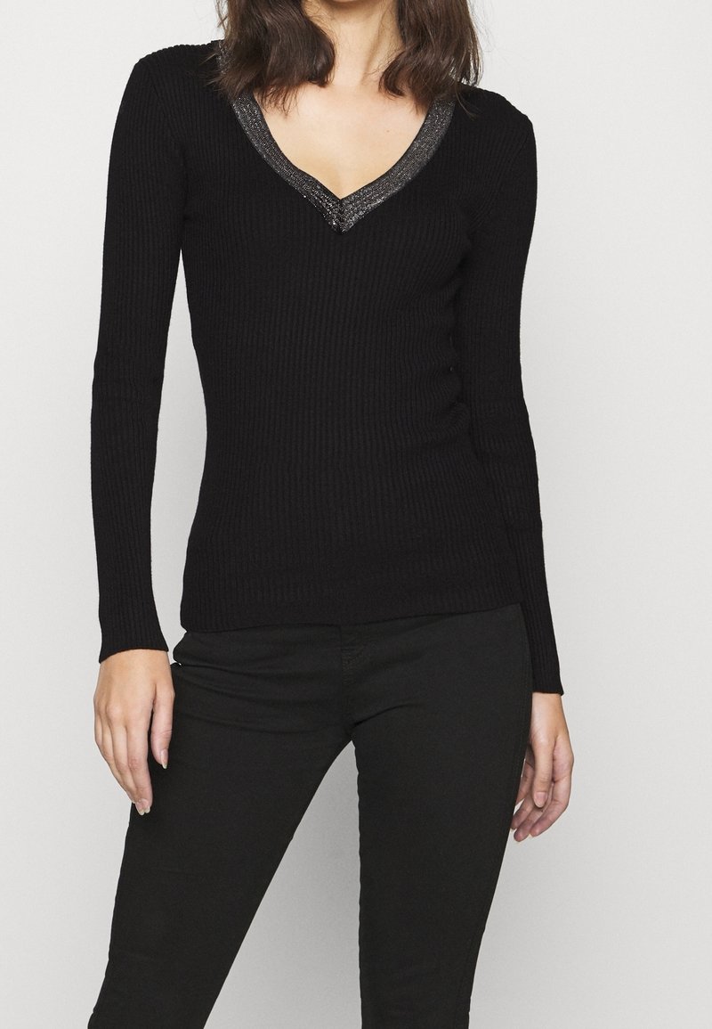 Haut noir à manches longues côtelé avec un décolleté en V profond, orné d'un accent métallique le long du cou. Texture lisse, coupe ajustée.