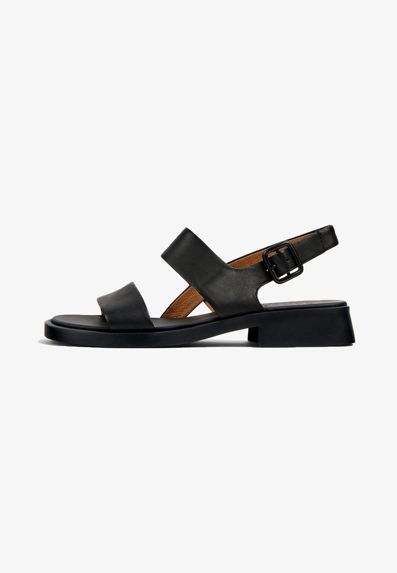 Black leather sandal with two horizontal straps and a buckled ankle strap. Flat, textured sole with a slight heel and a smooth finish.