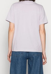 Ljus lavendelfärgad kortärmad t-shirt i mjuk bomull, med en avslappnad passform och enkel halsringning, i kombination med vida denimbyxor.