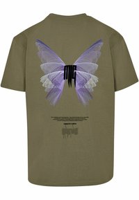 Olíva zöld póló, hátán nagy grafika purple pillangószárnyakkal, fekete betűkkel és szöveggel alatta.