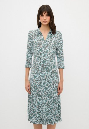 Blumen Kleid aus leichtem Stoff, mit einem grün-weißen Blumenmuster, kragenlosem Hals, dreiviertel langen Ärmeln und mittellanger Schnitt.