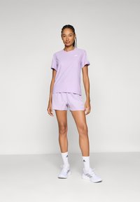 Lichtpaars sportoutfit bestaande uit een T-shirt met korte mouwen en bijpassende shorts, met subtiele branding en een comfortabele, gestructureerde stof.
