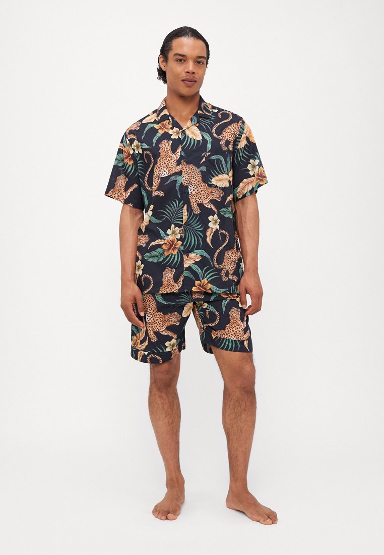 Chemise à manches courtes avec imprimé floral et shorts assortis ; fond sombre avec des léopards, des feuilles tropicales et des fleurs ; tissu léger.