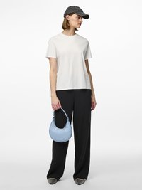 T-shirt en coton blanc, coupe ample, associé à un pantalon noir à jambes larges. Un sac à main en faux crocodile bleu clair et une casquette grise complètent la tenue.