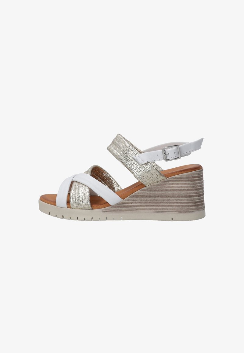 Wedge sandals with a white leather upper and metallic gold accents. Features crisscross straps and a textured wedge heel with a beige sole.