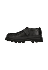 Zapato de cuero negro con punta redonda, costuras texturizadas y una suela de goma gruesa. Presenta una etiqueta decorativa en el lateral.