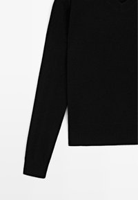Maglione nero lavorato a maglia con scollatura a V e maniche lunghe, caratterizzato da una texture morbida e un taglio corto sopra i fianchi.