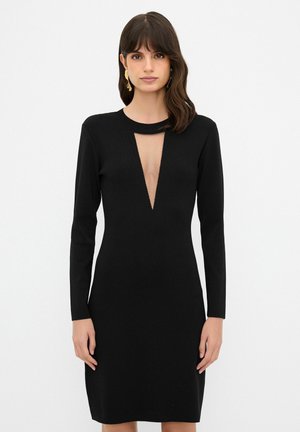 Schwarzes Kleid aus Strickstoff mit langen Ärmeln und einem tiefen V-Ausschnitt mit Ausschnittdetail. Figurbetonte Silhouette, glatte Textur.