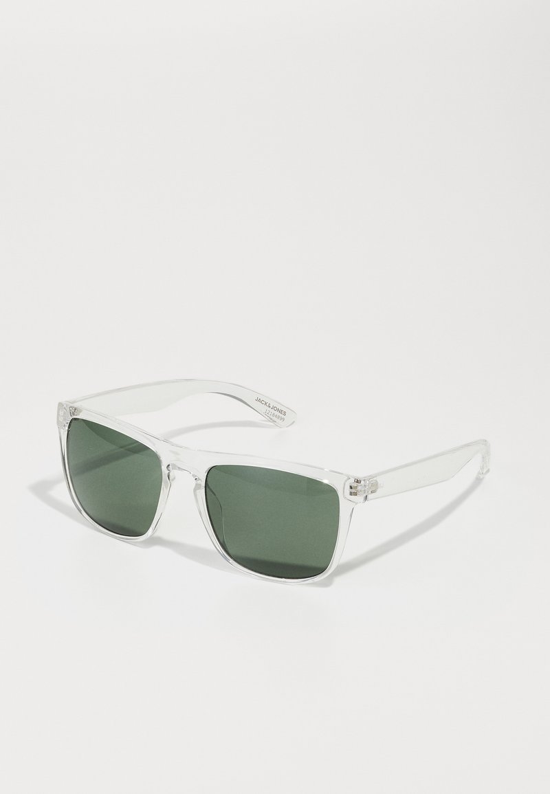 Ochelari de soare din plastic clar, cu lentile verzi, de formă pătrată și brațe transparente cu mici accente de hardware în față.