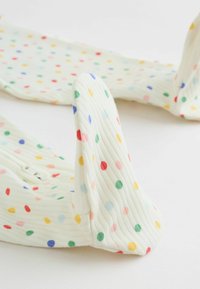 Collants blancs côtelés à pois colorés en rouge, vert, bleu, jaune et rose, étalés sur une surface blanche.