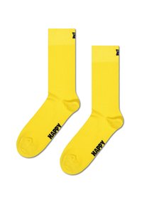 Żółte bawełniane skarpetki o gładkiej teksturze, z czarnym napisem "HAPPY" z boku oraz kontrastowym wzorem mankietu.