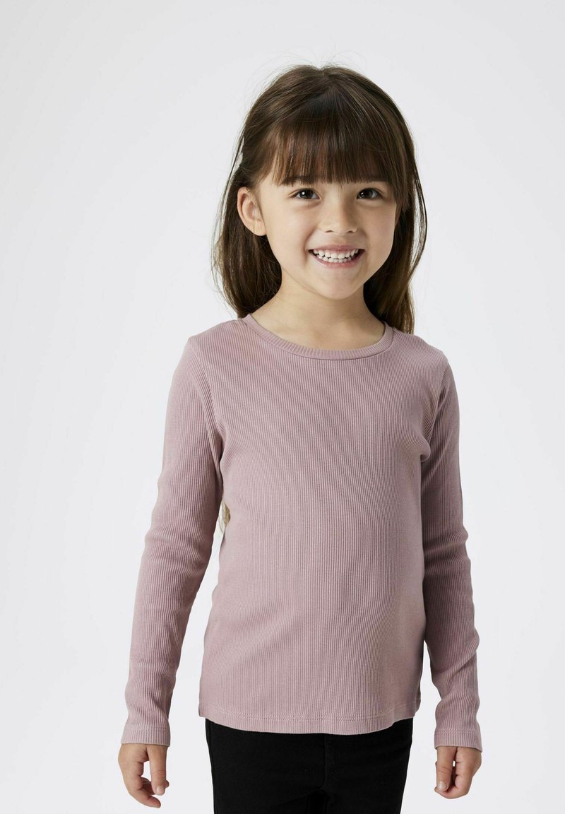 Helles rosa, geripptes Langarmshirt mit Rundhalsausschnitt und taillierter Passform, kombiniert mit schwarzen Hosen. Weicher Stoff und glatte Textur.