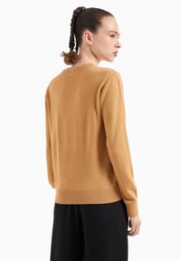 Maglione giallo senape con scollatura tonda, polsini e orlo a coste, realizzato in tessuto morbido, caratterizzato da un design semplice senza pattern.