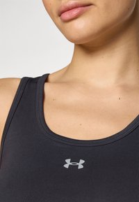 Fekete sportös tank top, kerek kivágással, szürke Under Armour logóval a mellkason és sima, testhezálló anyaggal.