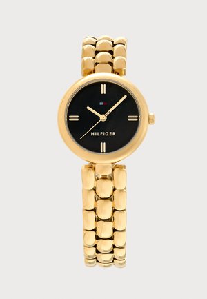 Montre-bracelet en métal ton or avec cadran rond noir, index horaires dorés minimalistes et marque "Hilfiger" sous le centre.