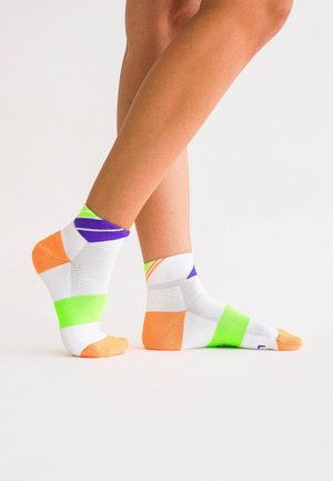 Bunte Sportsocken mit weißem Stoff und leuchtenden orangefarbenen, grünen, lila und blauen Abschnitten. Knöchellang mit strukturierten Mustern.