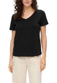 Czarna bawełniana koszulka z dekoltem w serek i krótkimi rękawami, o luźnym kroju i prostym dolnym zakończeniu. Brak widocznych wzorów lub akcentów.
