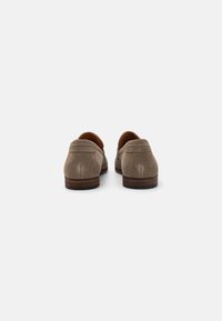 Suede loafers in light brown with a smooth texture, brown leather lining, a low heel, and contrasting dark brown outsole.