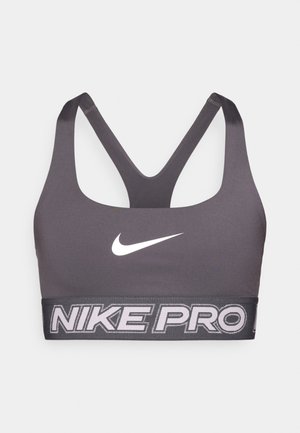 Αθλητικό σουτιέν Nike Pro σε σκούρο γκρι με ευρεία μαύρη ταινία που φέρει την επιγραφή "NIKE PRO" σε λευκό. Λείο ύφασμα και σχεδιασμός racerback για αυξημένη κινητικότητα.