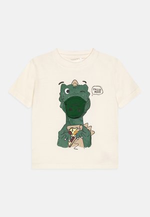 Camiseta de manga corta color crema con un gráfico de un dinosaurio verde sosteniendo una pizza, con el texto "FRESCO HUMOR" en un globo de diálogo.