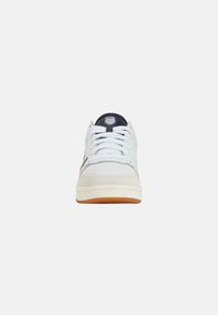 Sneaker bianco con tomaia in pelle liscia, linguetta in tessuto e suola in gomma. Presenta dettagli blu navy e lacci piatti. Design classico.