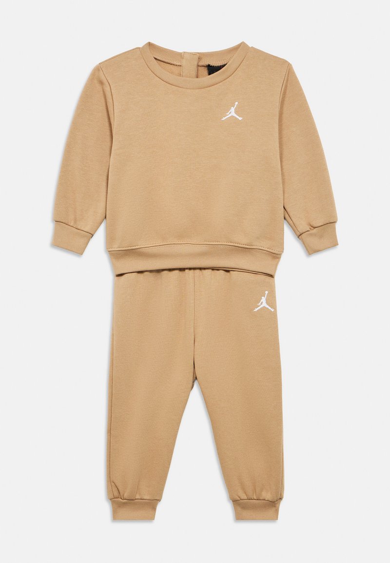 Μπεζ βαμβακερή φόρμα με μακρυμάνικη μπλούζα και παντελόνι. Διαθέτει ριμπ μανσέτες και λευκό λογότυπο στο στήθος και στον μηρό. Ομαλή υφή.