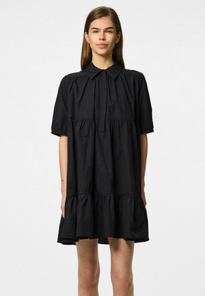 Vestido de algodón negro con un cuello tipo camisa, mangas cortas abullonadas, dobladillo con volantes recogidos y un corte relajado. Textura suave, sin patrones visibles.