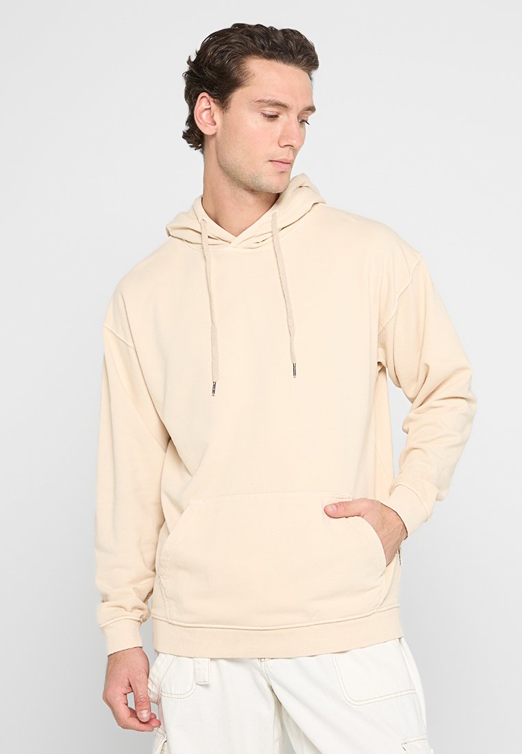 Felpa con cappuccio beige con tasca frontale, realizzata in tessuto morbido, dotata di cordini e dal fit rilassato. Adatta per un abbigliamento casual.